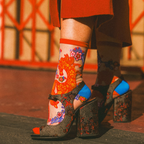 Close-up of hands adjusting the red cuff of a sheer floral horse sock, worn with dark sparkly open-toe block heels.