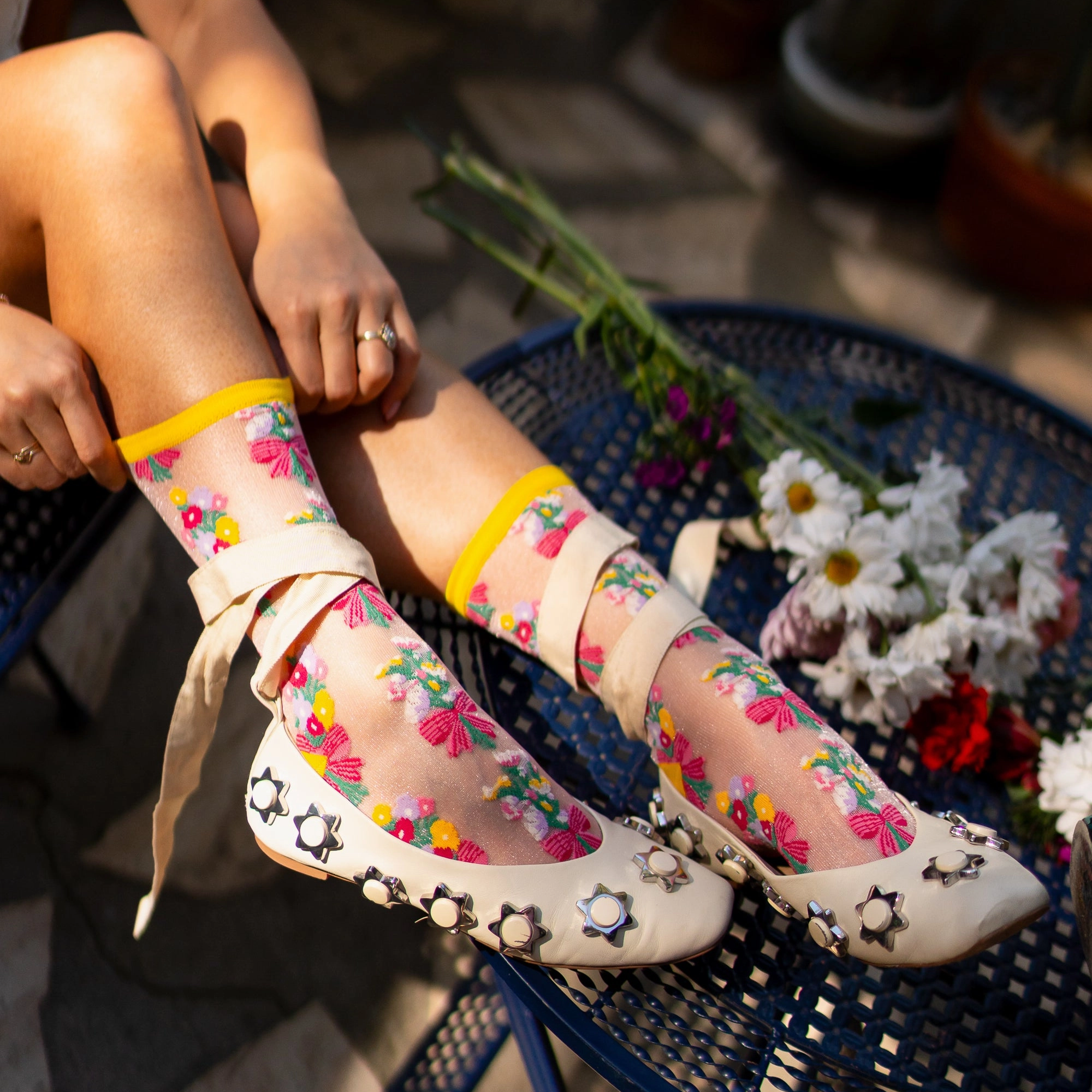 Detail view of sheer shimmer sock fabric showing a tiny bouquet of red, yellow, and purple flowers tied with a pink bow.