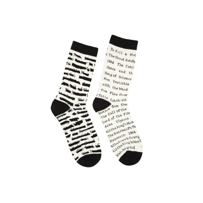Pair of cream crew socks with black stripes and text. Titles of banned books are printed on the socks, including 'To Kill a Mockingbird' and '1984'.