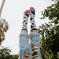 Legs kicked playfully into the air against a sky and palm tree backdrop showcase MOOOO! in White socks with pink toes. [lf]