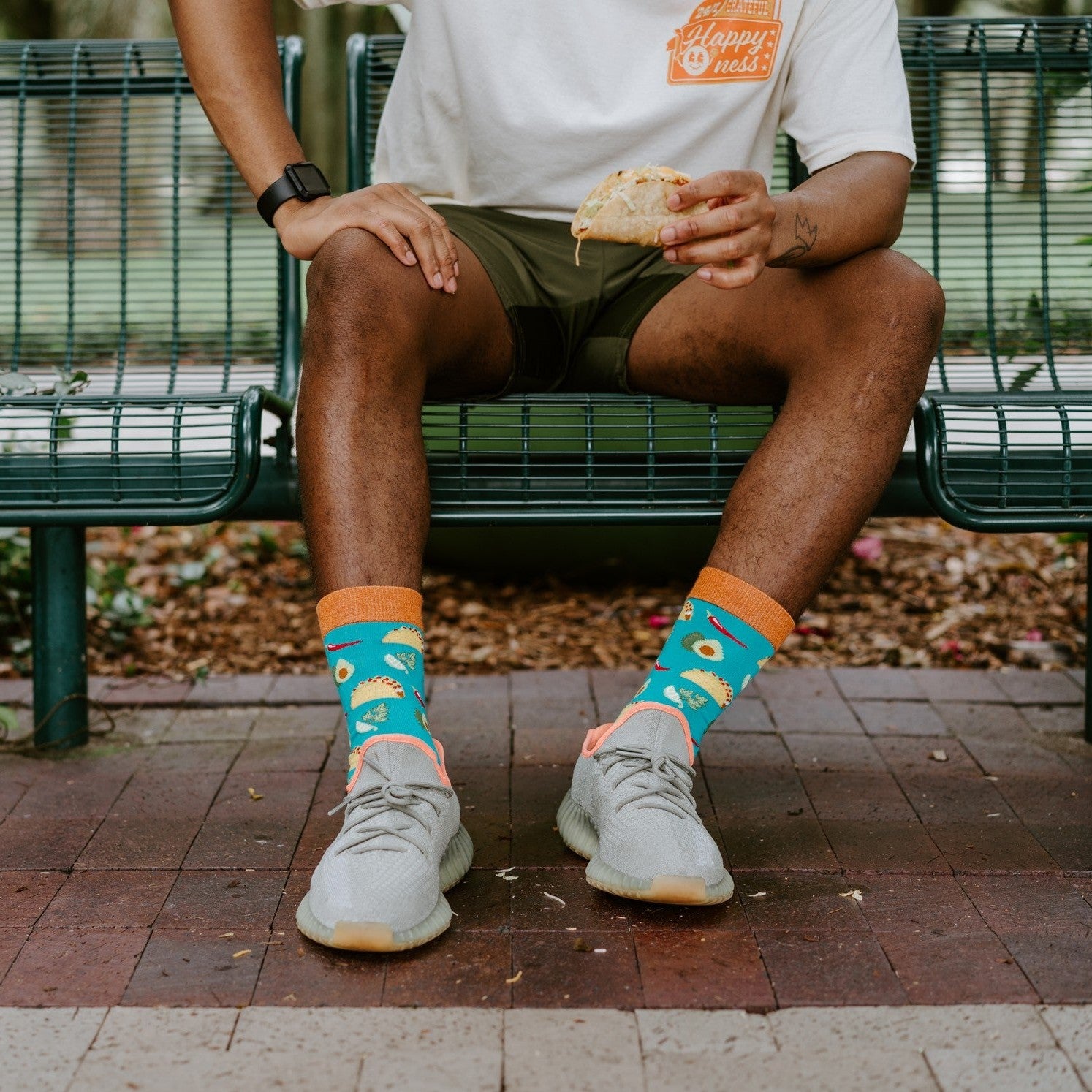 A lap-down crop on the bench highlights the avocado and taco motifs running across the Something To Taco Bout Bamboo in Blue socks above grey trainers. [lf]