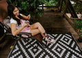 From across the diamond-patterned rug, a relaxed seated pose highlights Dragonfruit in Charcoal Heather socks while she stirs her drink with a spoon. [lf]