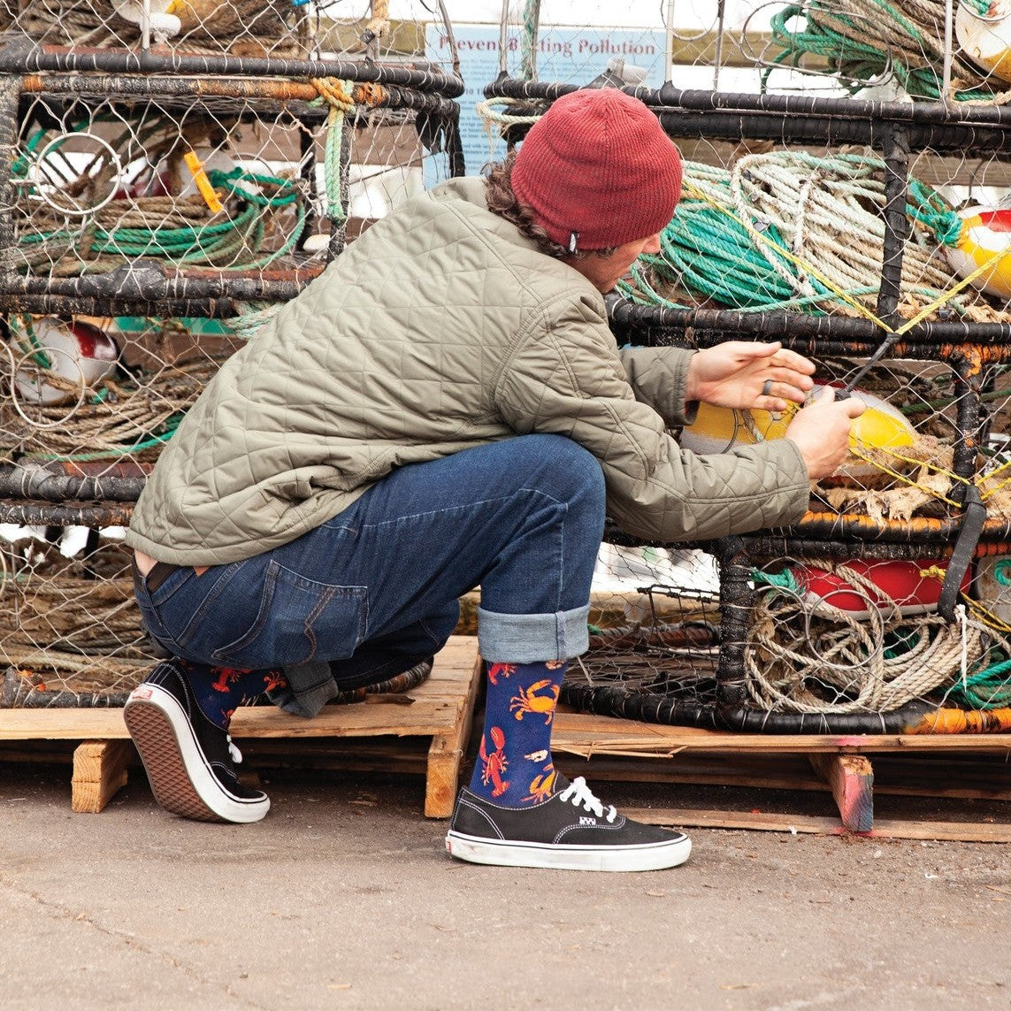 A friend lifts a wine glass at a seafood spread, modeling Seafood Platter socks with platter graphics. [lf]