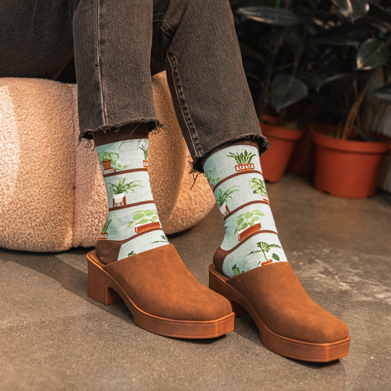 A friend reaches up to dust a tall philodendron, modeling Houseplants Bamboo socks in Blue with houseplant graphics. [lf]