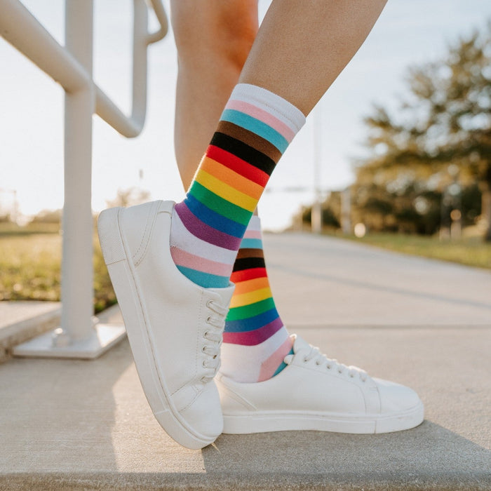 A close-up of Progress Stripes socks in Multi on a striped beach towel, the colors blending with a sunlit day. [lf]