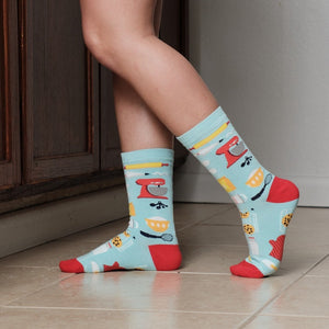 A close-up of Bake It Till You Make It Bamboo socks in Blue on a person reaching into the oven with mitts. [lf]