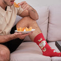 A close-up of Crab Rangoon socks in Red featuring crab rangoon illustrations, on a person seated at a Chinese-takeout dinner. [lf]