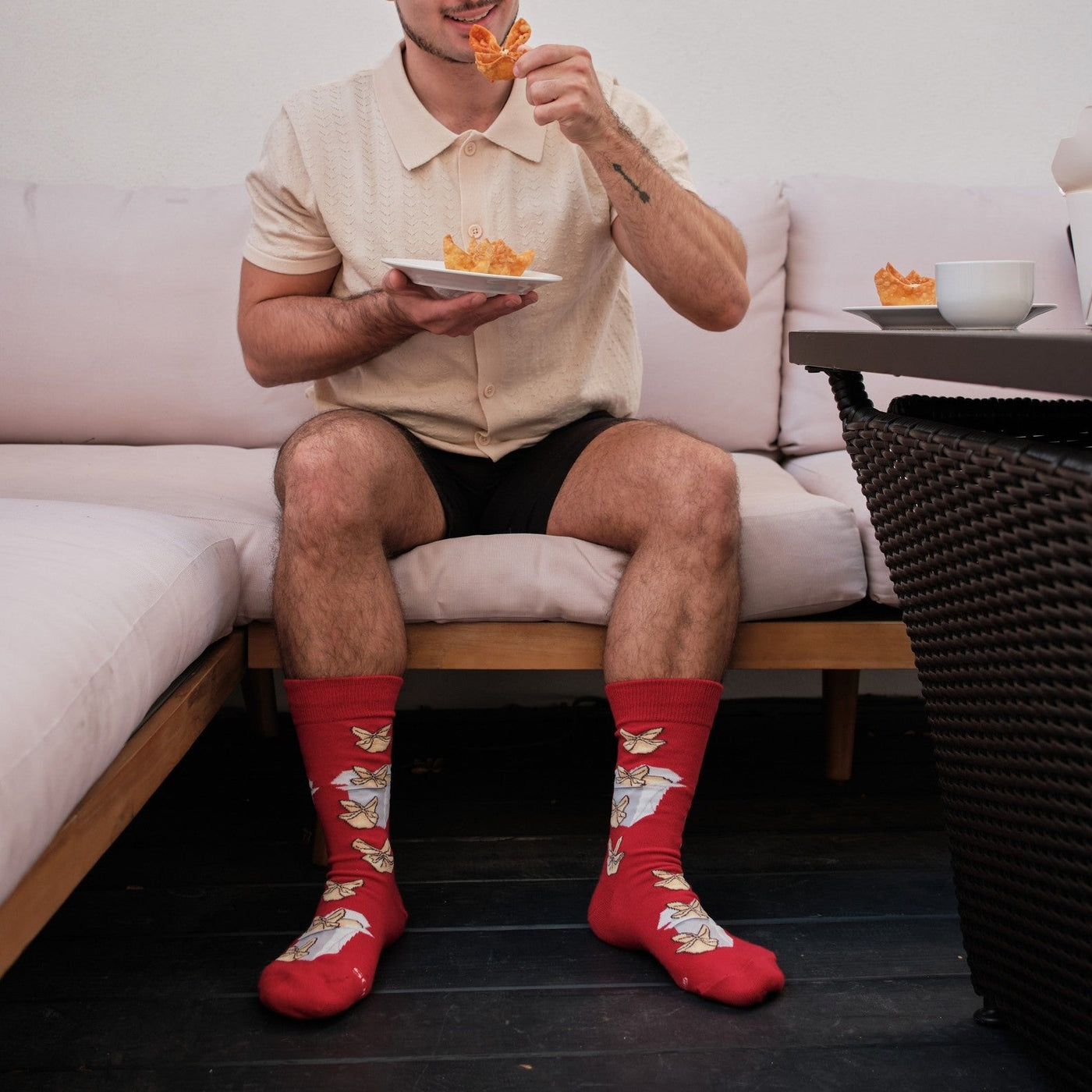 A pair of Crab Rangoon socks in Red stretched across a picnic blanket beside crab rangoon and dipping sauce. [lf]