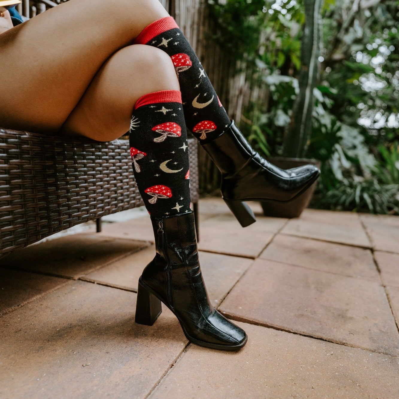 A close-up of Mystic Microdose socks in Black on a person seated beside a record player and incense burner. [lf]