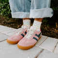 A couple laughs together on a porch swing, both modeling Spectrum of Love socks in Ivory with rainbow love motifs. [lf]