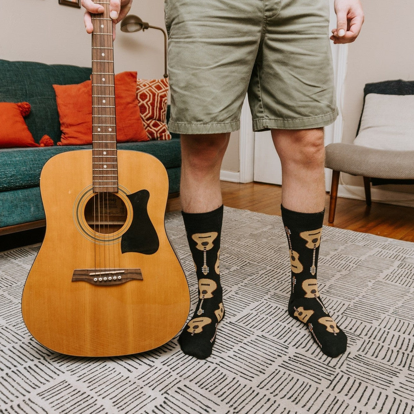A close-up of Guitars XL socks worn with rolled jeans and brown sneakers on a sunny outdoor staircase. [lf]