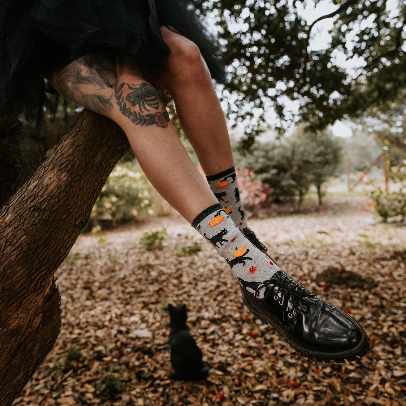 A close-up of Black Cat Halloween socks worn with shiny black boots, a black tulle skirt cropped above the calf. [lf]