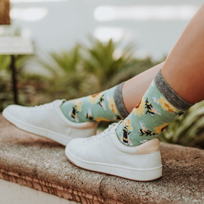 Honey In The Bank Bamboo socks with cheerful bee prints shown in a relaxed outdoor portrait. [lf]
