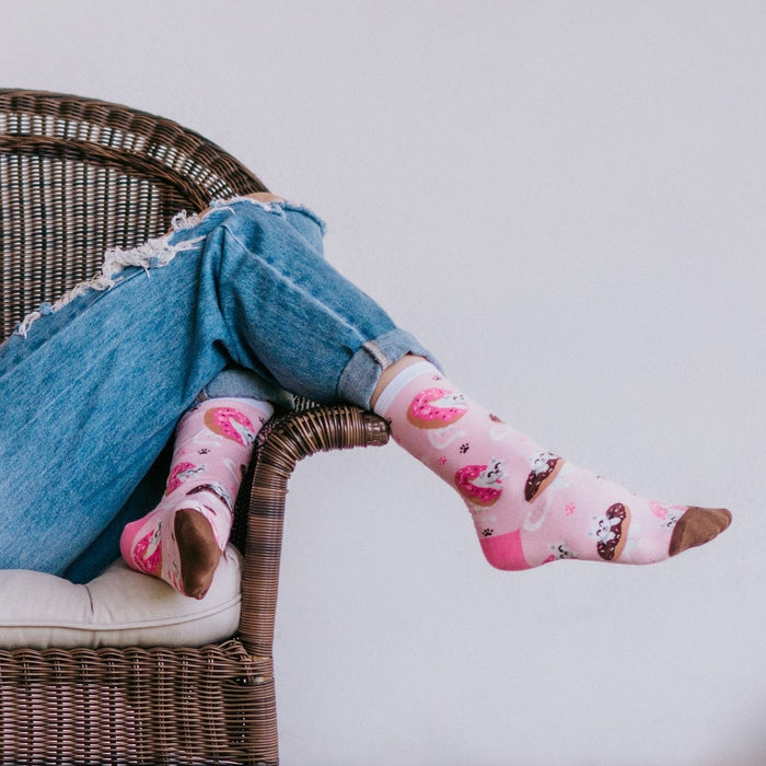 Sweet Treat Kitties pink socks displayed in their packaging atop a colorful donut and sprinkles flat-lay. [lf]
