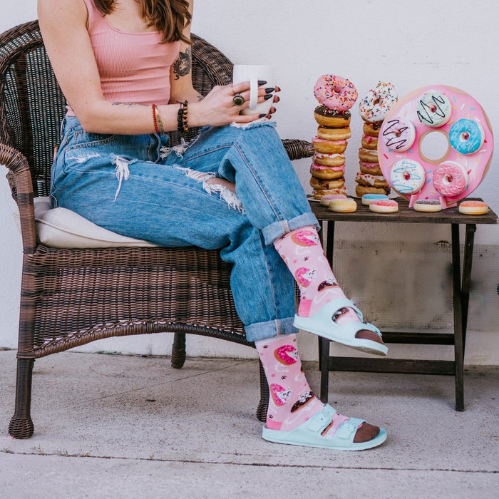 Sweet Treat Kitties socks featuring white cats peeking out of donuts shown packaged with Sock Smith branding amid a sprinkle-covered backdrop. [lf]