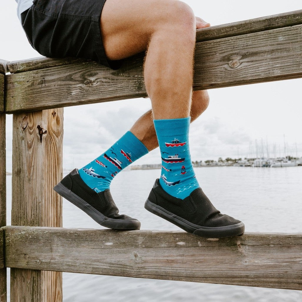 Don't Rock The Boat blue socks paired with shorts and slip-ons in a breezy harbor lifestyle photo. [lf]