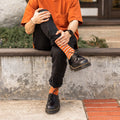A close-up of feet wearing Sailor Stripe Bamboo socks tucked into classic leather Oxfords on a textured rug. [lf]