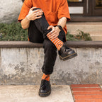 A close-up of feet wearing Sailor Stripe Bamboo socks tucked into classic leather Oxfords on a textured rug. [lf]