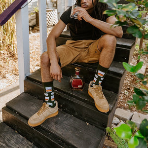 Whiskey Business Bamboo green bamboo socks paired with tan sneakers in a curated outdoor cocktail flat-lay. [lf]