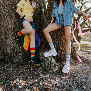 A bright lifestyle shot of Pride Stripes rainbow socks worn with athletic shorts and skate sneakers. [lf]