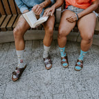 Socks And Sandals socks worn with classic leather sandals on a model relaxing on a wooden park bench. [lf]