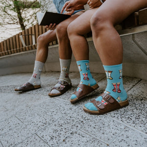 Socks And Sandals shown in styled detail on a couple's feet, leather Birkenstock-style sandals layered over striped knit. [lf]