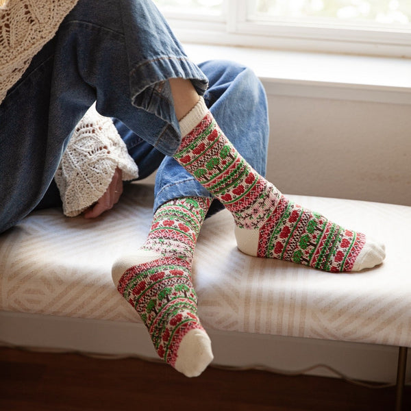 A close-up of Apple Trees socks featuring tiny apple trees on a fair-isle knit, shown above blue jeans. [lf]