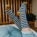 Close-up of two feet pointed upward, highlighting the navy stripes and mustard heel of Sailor Stripe Bamboo socks in Charcoal White. [lf]