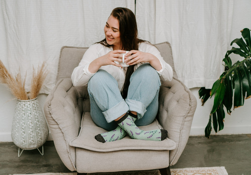 Smiling laugh on a tufted armchair, denim cuffs rolled above charcoal-toed mint green lavender socks, paired with the Lovely Lavender Bamboo socks in Green Heather. [lf]