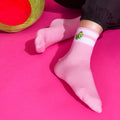 [lf] Person wearing pink striped socks with a cute green character, relaxing on a fuchsia surface.