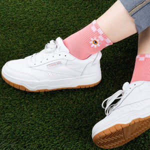 [lf] Pink socks with white stripes and daisy embroidery, paired with white sneakers on green grass.