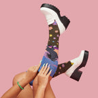 [lf] Legs up, model showcases colorful floral and abstract socks with white platform loafers.
