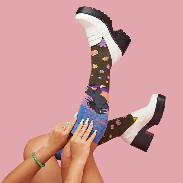 [lf] Legs up, model showcases colorful floral and abstract socks with white platform loafers.