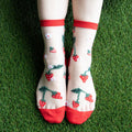 [lf] Legs on green grass wearing sheer socks with red strawberries and white flowers.