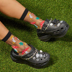 [lf] Legs crossed on grass, model wears sheer black socks with colorful mushroom patterns.