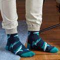 [lf] Person in beige joggers wears navy socks with teal and white shark patterns.