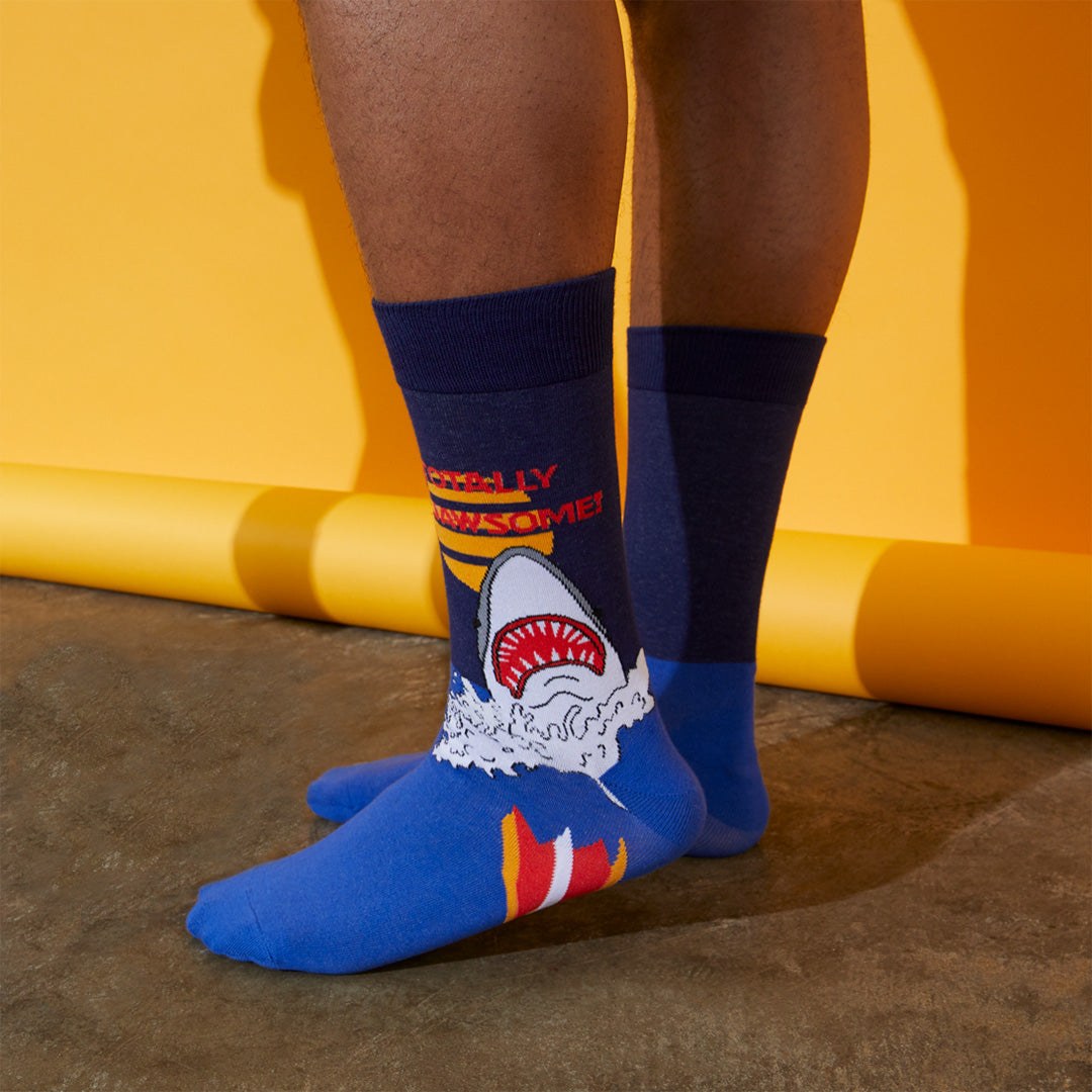 [lf] Person stands wearing navy and blue shark-themed socks with "REALLY AWESOME!" text.