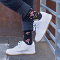 [lf] Person in black jeans and white sneakers shows off mushroom-patterned socks with a pun.