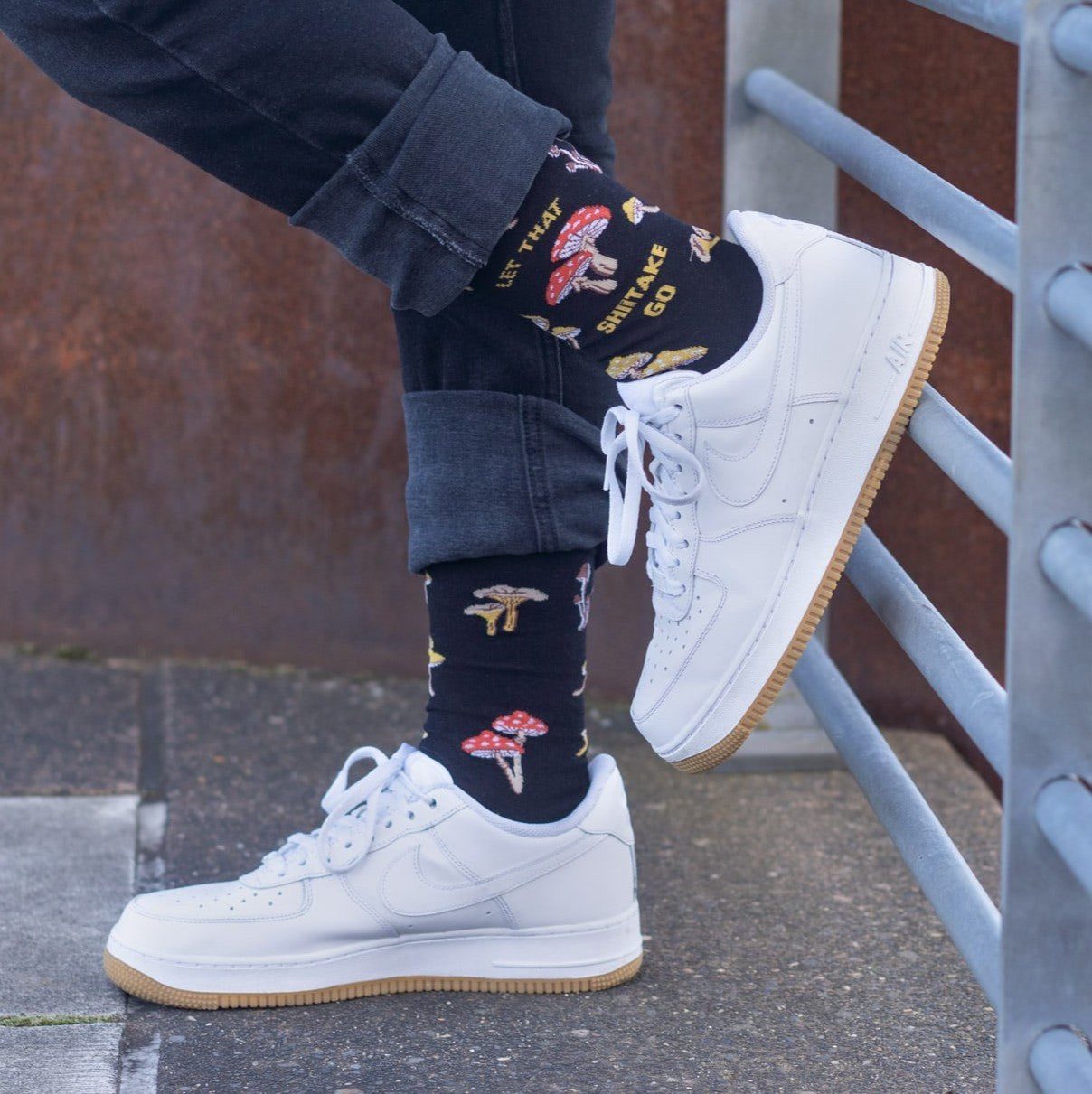 [lf] Person in black jeans and white sneakers shows off mushroom-patterned socks with a pun.