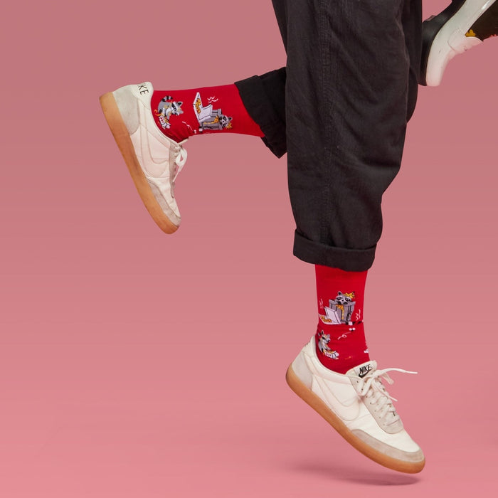 [lf] Playful raccoons on red socks, worn by a model in black pants and white sneakers.
