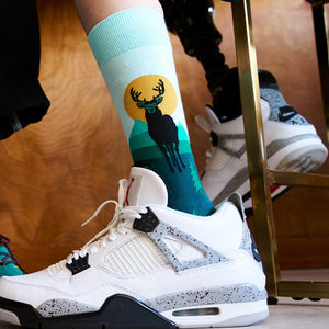 [lf] Person wearing white sneakers and teal socks with a deer and sunset design.