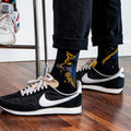 [lf] Person wearing black cat socks with yellow and blue accents, black pants, and sneakers.