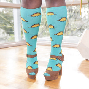 [lf] Model stands wearing blue knee-high socks with taco dinosaur pattern and brown platform heels.