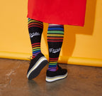 [lf] Model wearing black "Pride" socks with rainbow stripes and platform shoes on a yellow background.