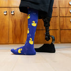 [lf] Person with prosthetic leg wears blue socks with yellow rubber duckies and bubbles.