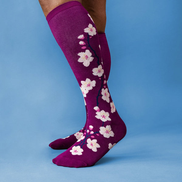[lf] Person wearing purple knee-high socks with white cherry blossoms on a blue background.