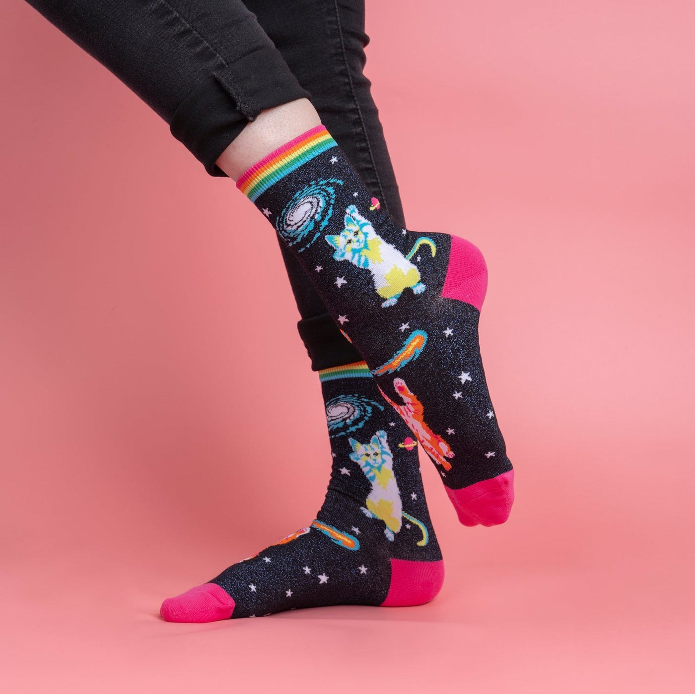 [lf] Person in black jeans models dark socks with space cats, galaxies, and bright pink toes.