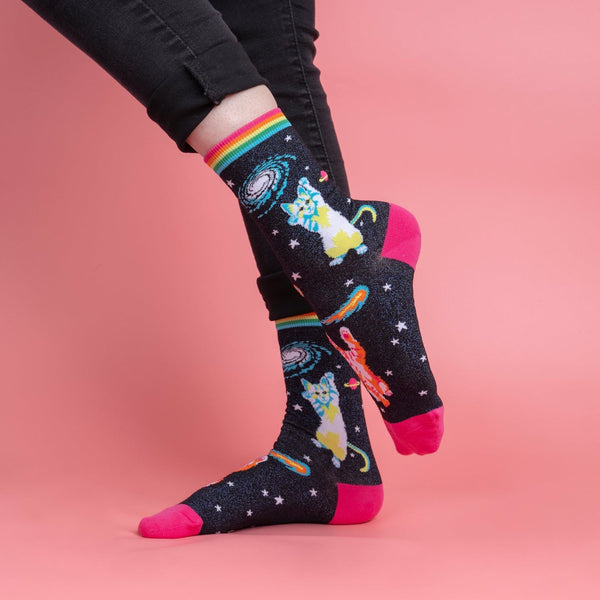 [lf] Person in black jeans models dark socks with space cats, galaxies, and bright pink toes.