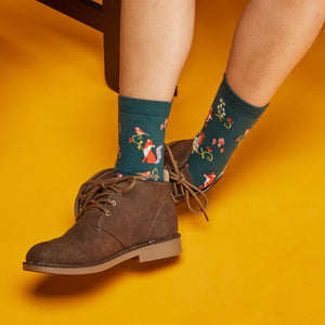 [lf] Person wearing brown boots and forest-themed green socks with foxes and birds.