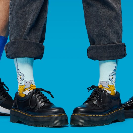 [lf] Person in black shoes and cuffed jeans wears light blue socks with cute animal patterns.